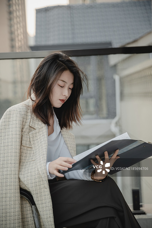 亚洲女性白领在开放办公区阅读文件图片素材