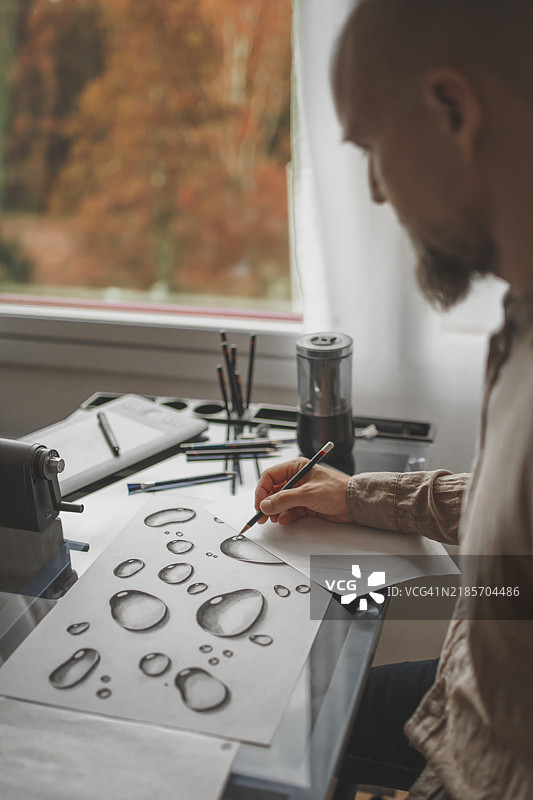 创意男士在绘图桌上工作，设计师在家中素描，男性企业家在进行设计项目，男性艺术家绘制草图图片素材