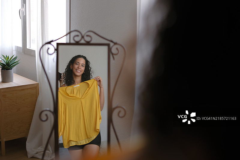 年轻女性在家试穿衣服并照镜子图片素材