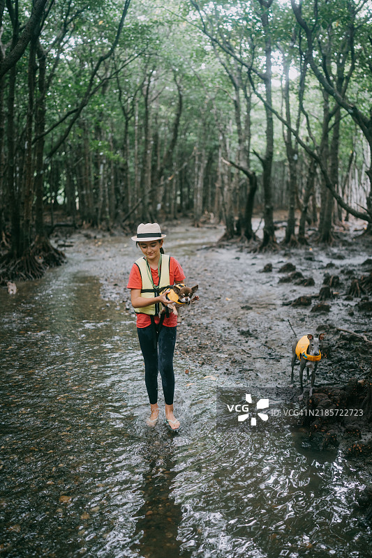 年轻女孩在日本冲绳的红树林中照顾她的狗图片素材