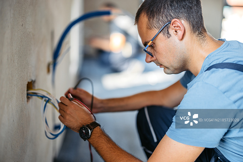 电工在空置的正在装修的公寓中处理电缆图片素材