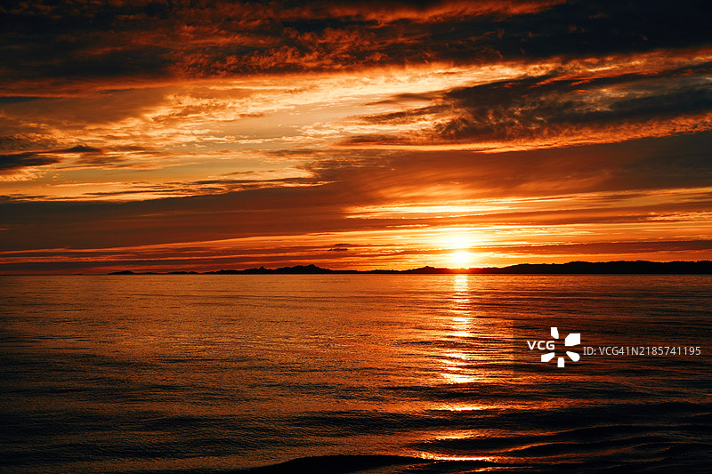日落时分，海面与戏剧性的天空相映成趣，挪威罗加兰州桑德维的美丽景色图片素材