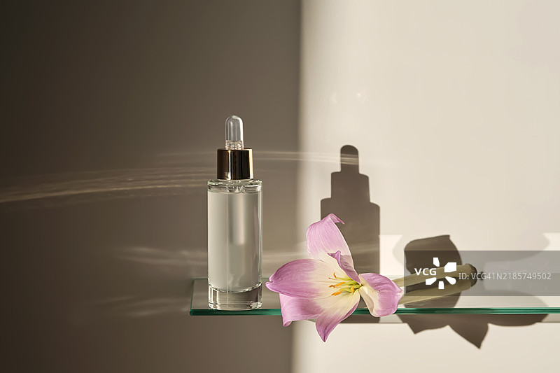 浴室玻璃架上的滴管面部精华液。图片素材