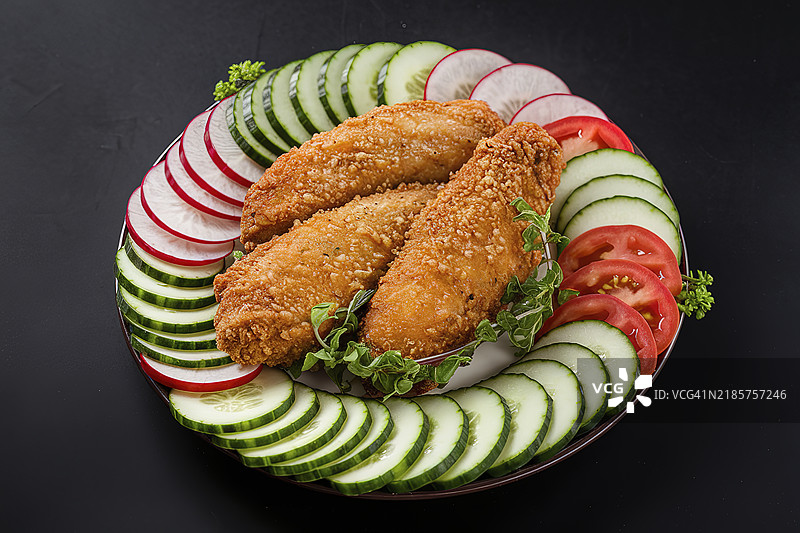 一盘炸鸡胸肉配新鲜黄瓜、西红柿和萝卜图片素材