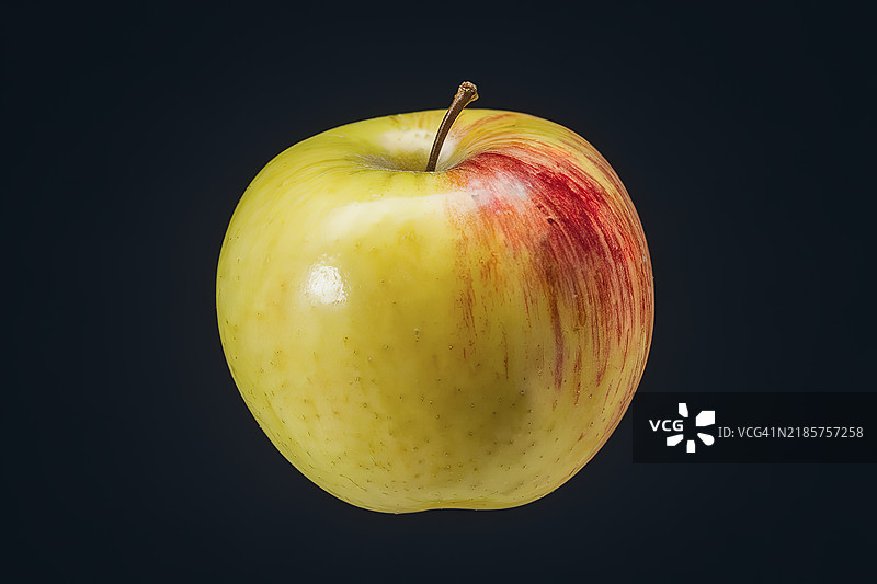 一只带有淡红晕的黄色苹果，孤立在黑色背景上图片素材