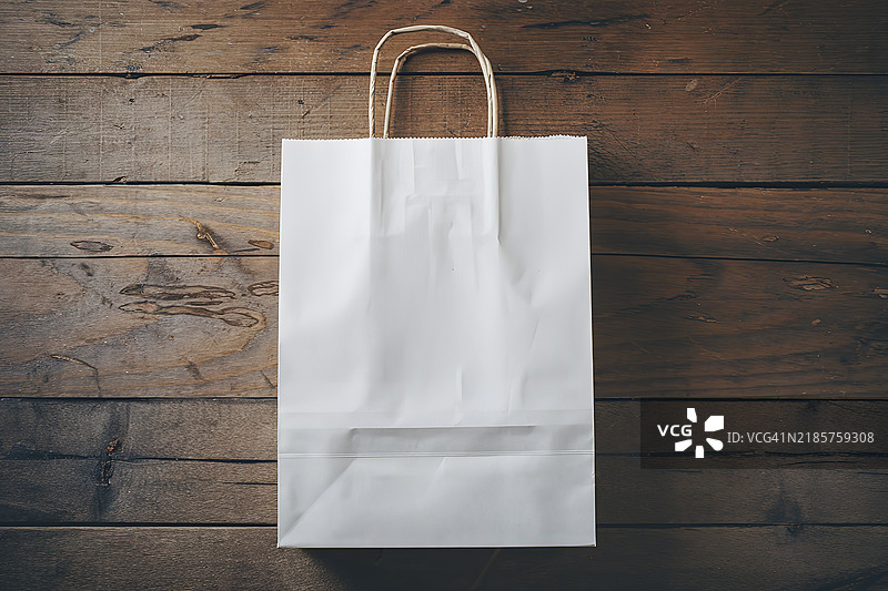 一个空白标签的纸购物袋放在木质背景上图片素材