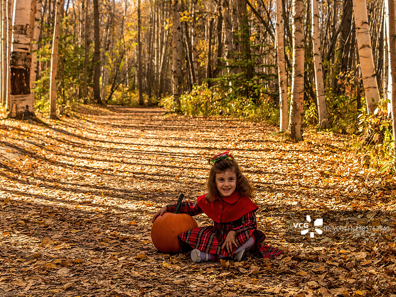 女孩在森林中玩秋天的落叶图片素材