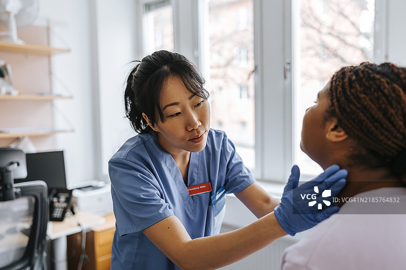 女性医学专家在医院的检查室检查年轻患者的淋巴结图片素材