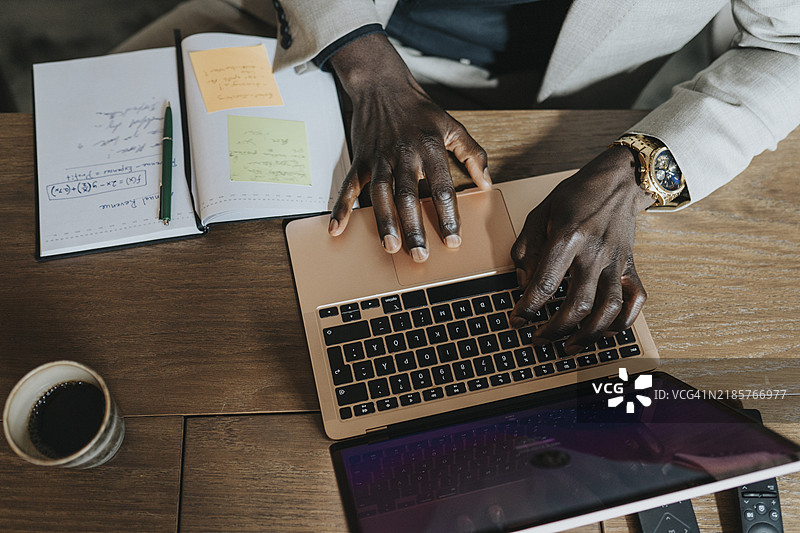 商人坐在桌子前用笔记本电脑打字的手图片素材