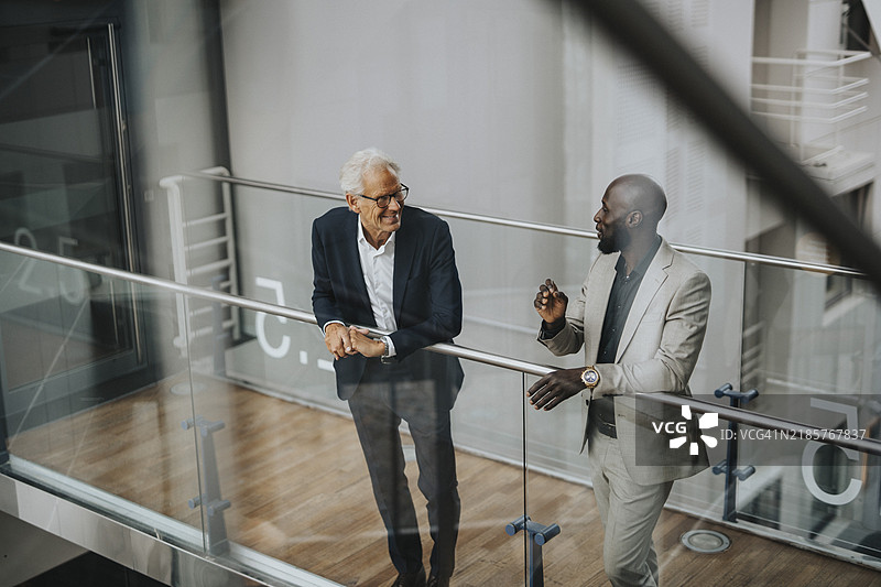 微笑的商人在玻璃栏杆旁讨论图片素材
