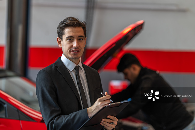 自信的商人在汽车修理店监督检查过程图片素材