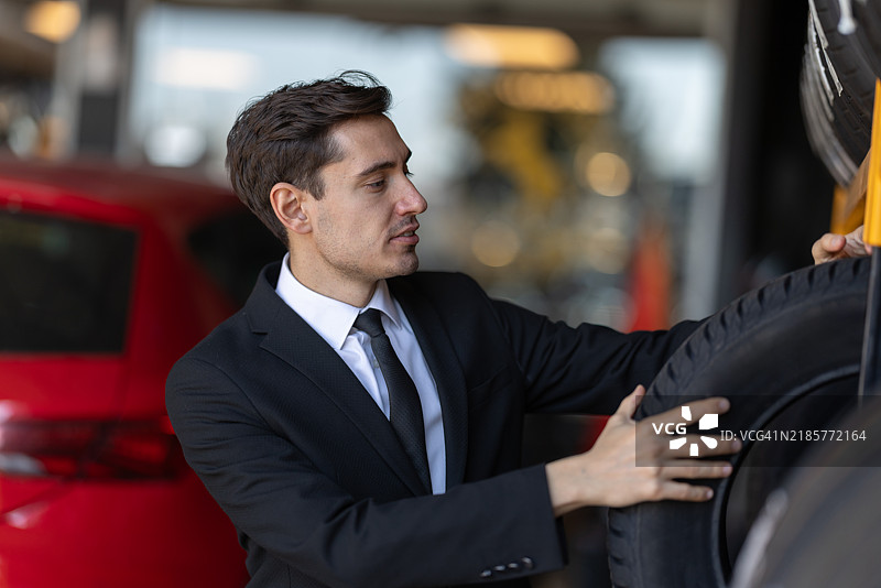 穿西装的专业人士在汽车经销商处检查轮胎图片素材