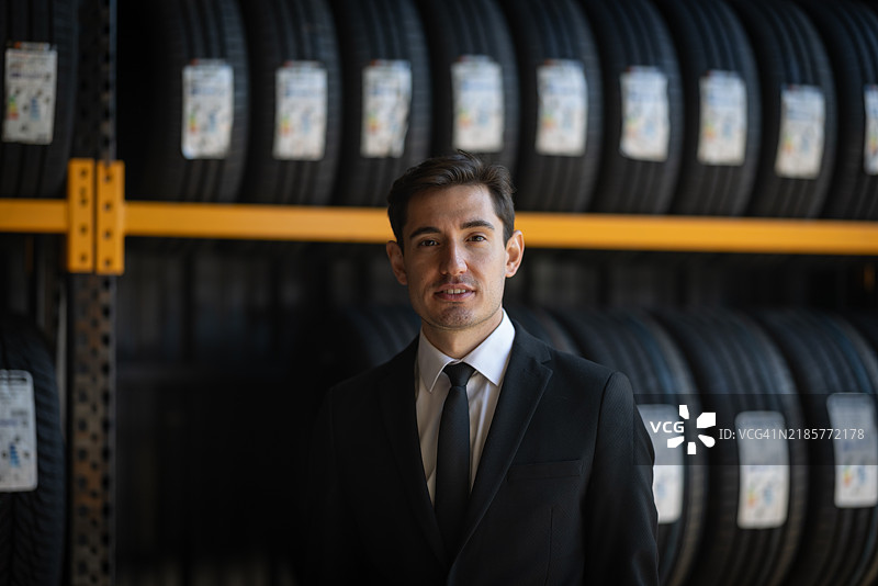 自信的商人在轮胎仓库中穿着西装站立图片素材