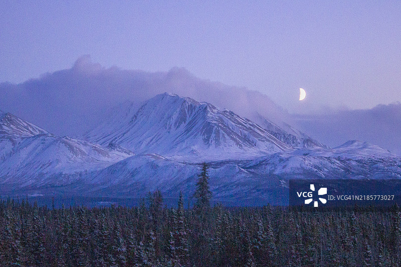 新雪覆盖的山峰上升起的月亮图片素材