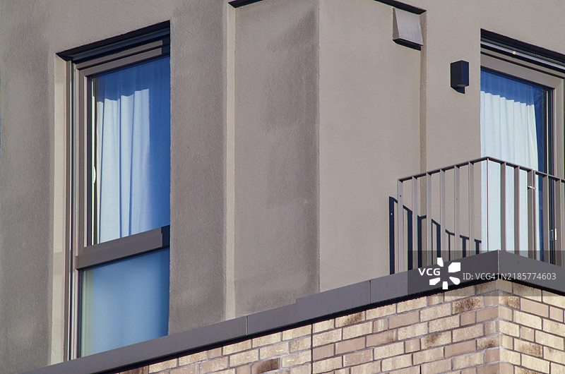 现代住宅建筑的细节，展示了阳台、窗户、窗帘以及一抹蓝天的景象图片素材