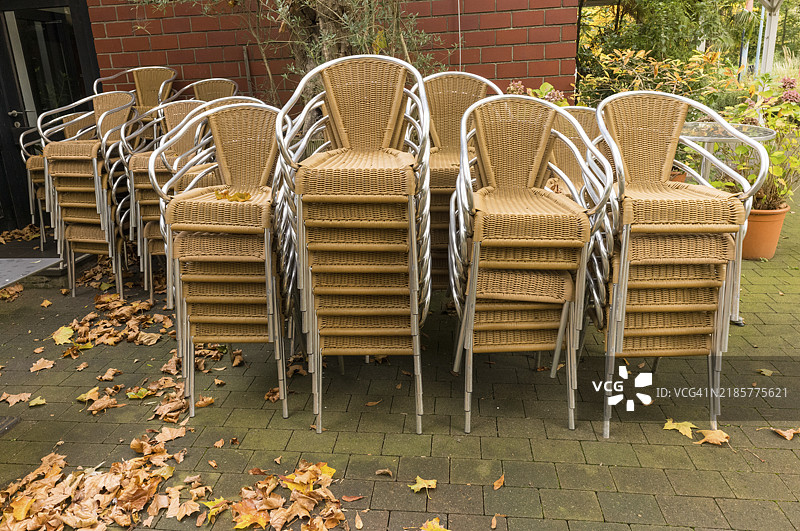 秋天的露台上，许多空椅子叠放在一起，静静等待顾客。图片素材