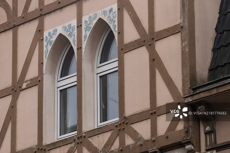 迷人的半木结构房屋展示了两个带有精美蓝色花卉图案的拱形窗户图片素材