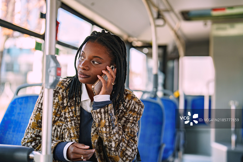 年轻的非洲女性在公共汽车上打电话。图片素材