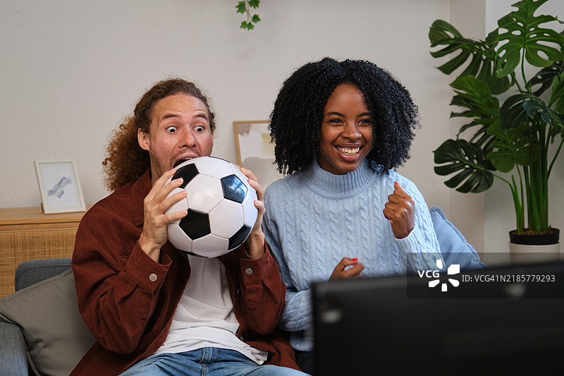 兴奋的情侣在家看足球比赛时欢呼雀跃图片素材