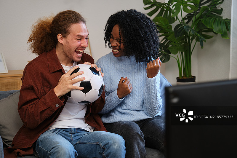 兴奋的情侣在家观看足球比赛时欢呼图片素材