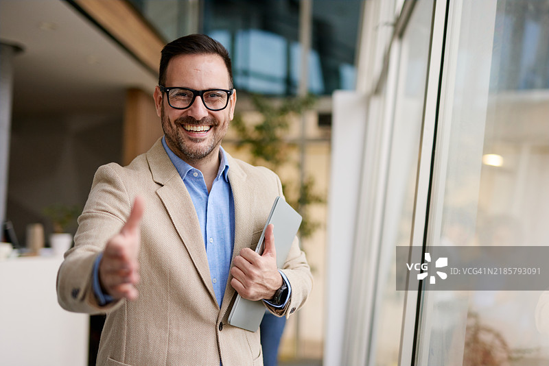 友好的商人在现代办公室中伸出手握手图片素材