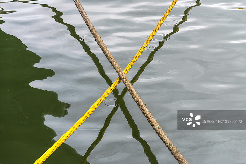 两根船缆交叉悬挂在水面上图片素材