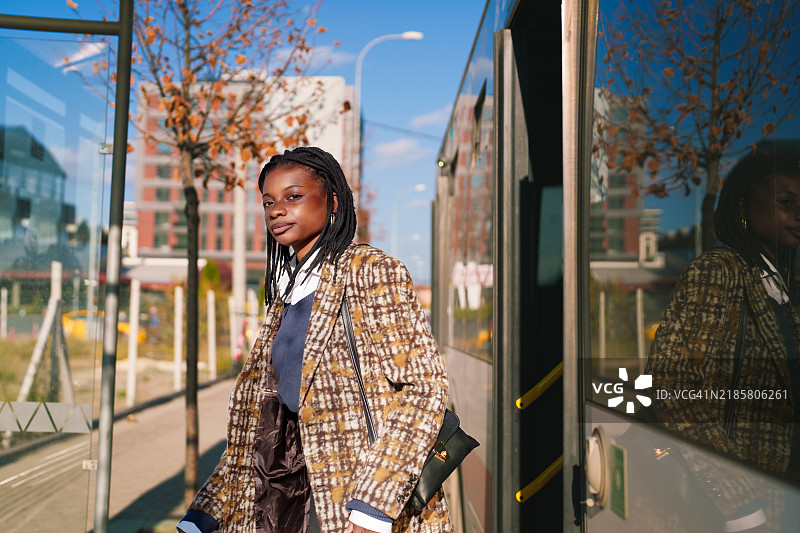 年轻的非洲女性走出公共交通工具。图片素材