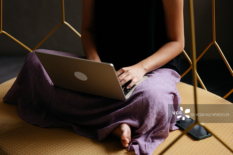 亚洲女性坐在舒适的吊床上，正专心使用她的笔记本电脑。图片素材