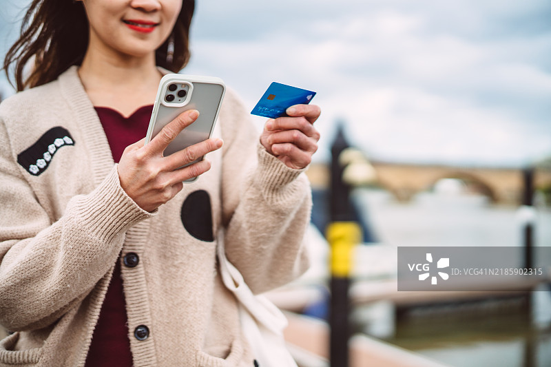 女人在河边用智能手机网上购物图片素材