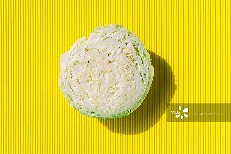 半个卷心菜在阳光明媚的黄色背景上图片素材