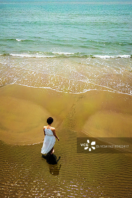穿着白色裙子的女士在海滩上散步图片素材