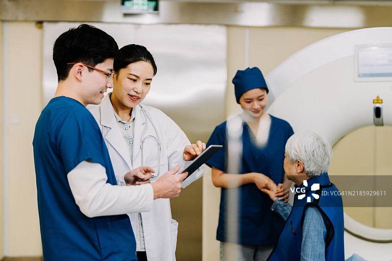 亚洲女性医生和男性护士正在分析数字平板上的X光图像。图片素材