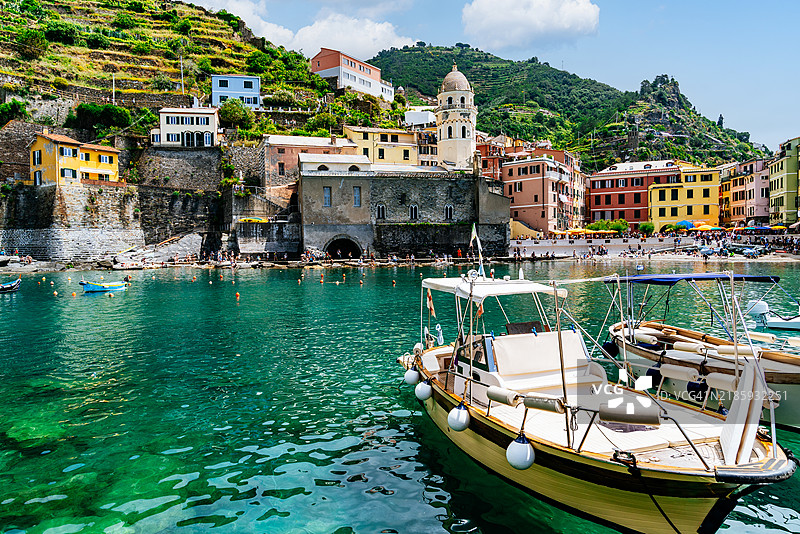 维尔纳扎村和教堂的海岸景观，清澈的蓝色海水和前景中的船只，四周环绕着梯田山丘。图片素材