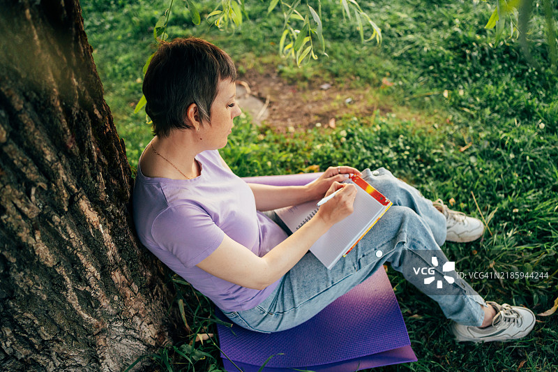 宁静的作家在黄金时刻享受自然的宁静，记录笔记并寻找灵感图片素材