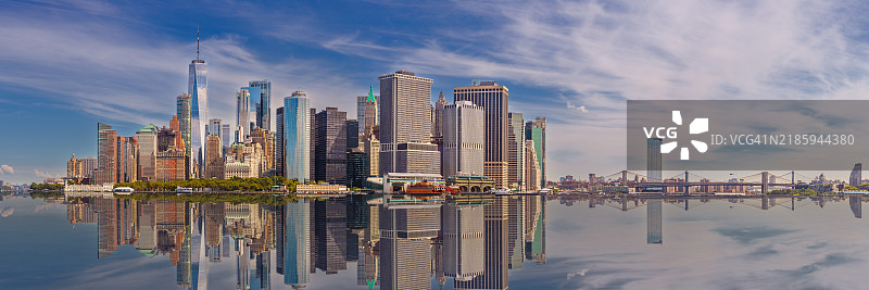 纽约市天际线，包括曼哈顿金融区、世贸中心、布鲁克林和曼哈顿大桥，以及蓝天和白云。图片素材