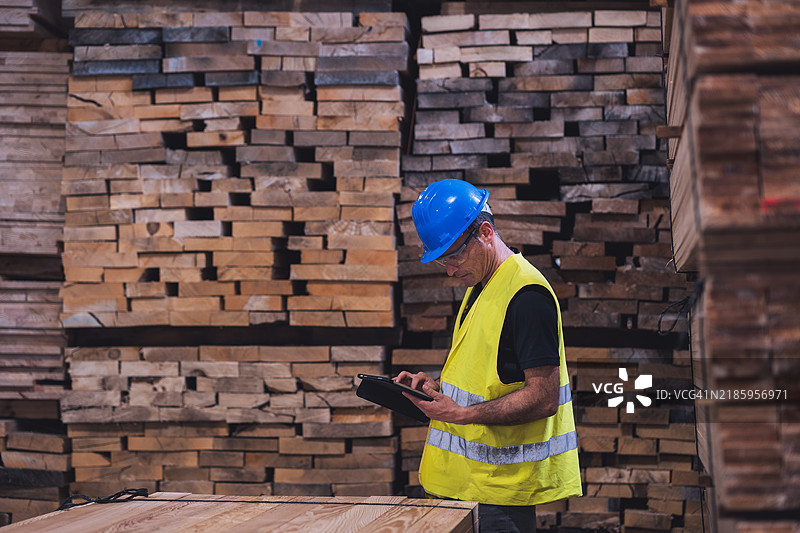 木匠在木材仓库使用数字平板电脑图片素材