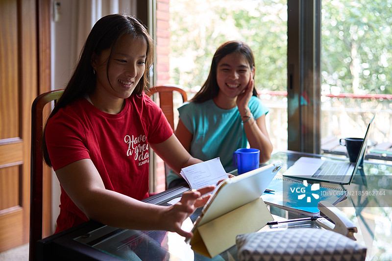 中国女学生在家中使用平板电脑合作完成项目图片素材