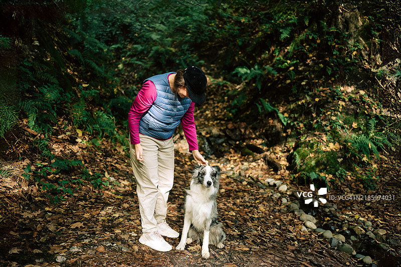 女人在郁郁葱葱的森林中与她的狗享受时光图片素材