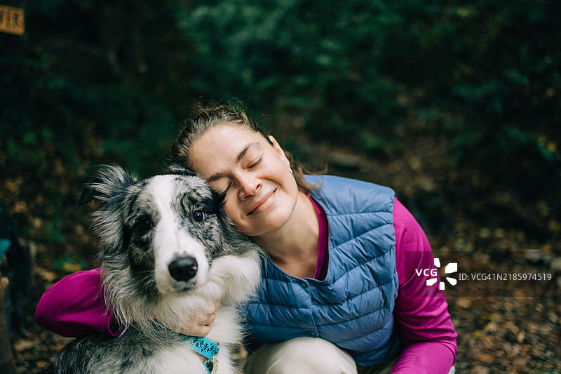 微笑的女人和她忠诚的狗在森林中度过时光图片素材