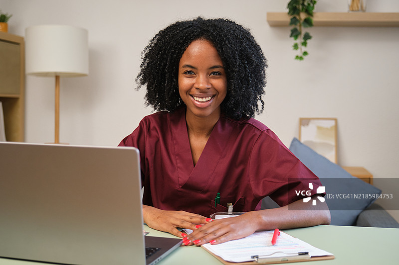 微笑的年轻医生在家中使用笔记本电脑工作图片素材