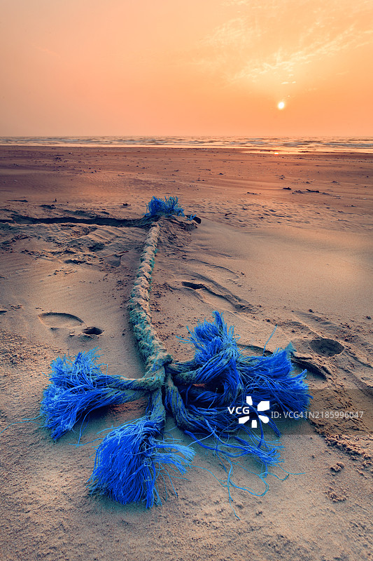在立陶宛的波罗的海海滩上，日落时分，一段蓝色绳索的特写镜头。图片素材