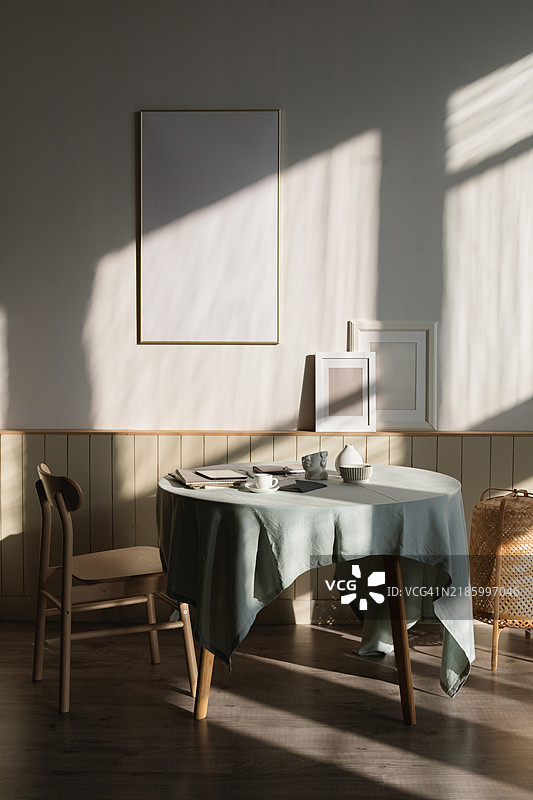 阳光透过窗户洒在时尚的餐厅里，桌子上摆放着各种装饰品和文件。图片素材