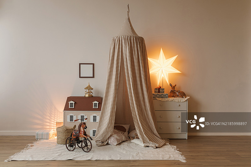 儿童卧室里，马玩具近景，前面是洋娃娃屋、帐篷和装有礼物的抽屉柜。图片素材