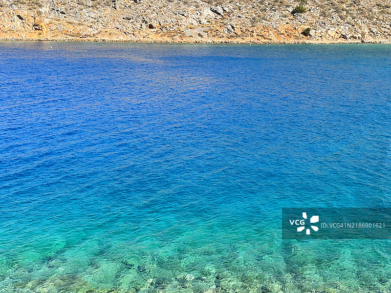 希腊萨罗尼克群岛海德拉岛曼德拉基湾的碧绿色海水和海岸线特写图片素材