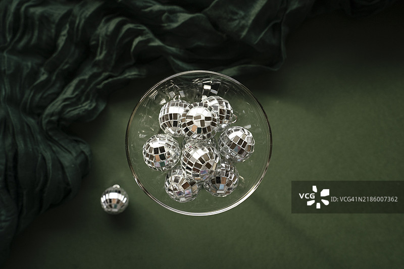 香槟杯里装满了镜面迪斯科球装饰，背景为绿色天鹅绒。新年派对概念。图片素材