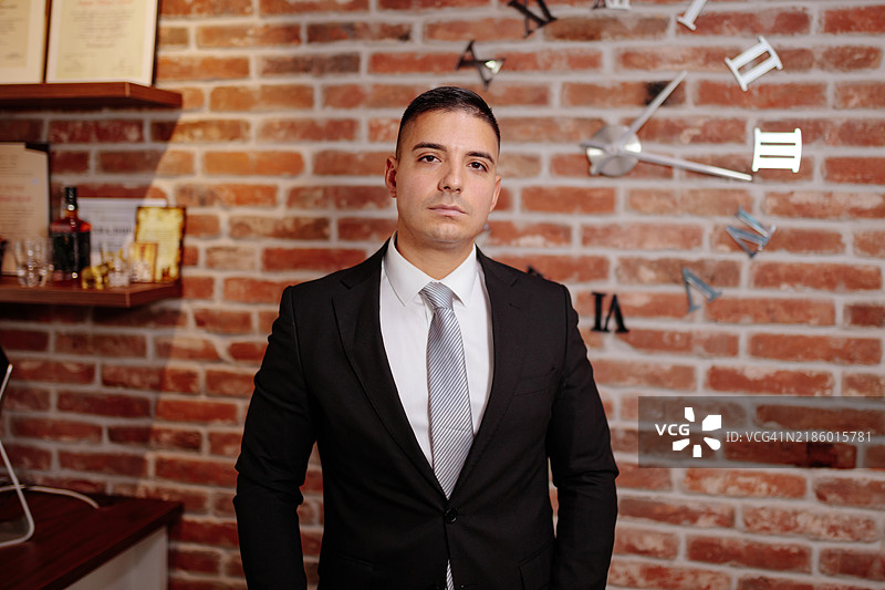 自信的商务专业人士穿着正式服装站在砖墙前图片素材