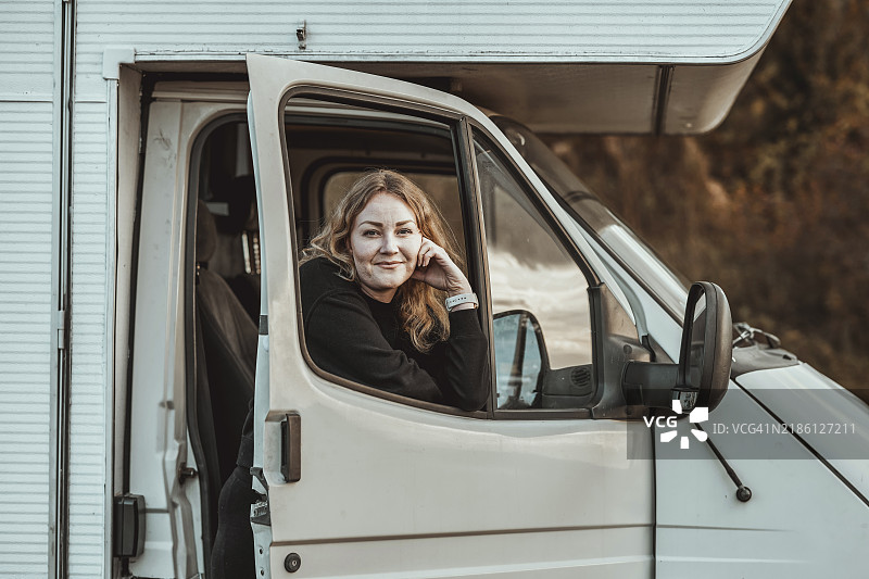 中年女性在房车窗户旁望外。图片素材