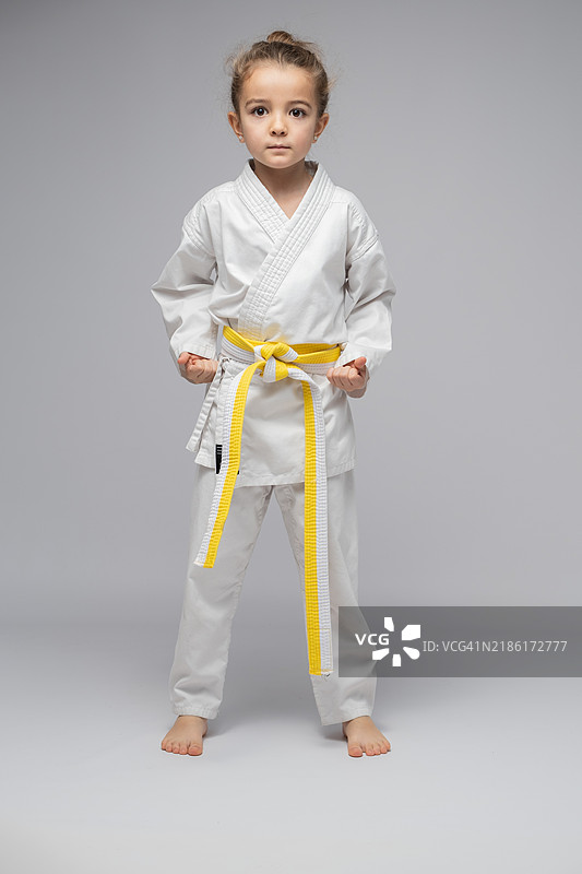 年轻女孩在灰色背景上摆出战斗姿势练习空手道图片素材