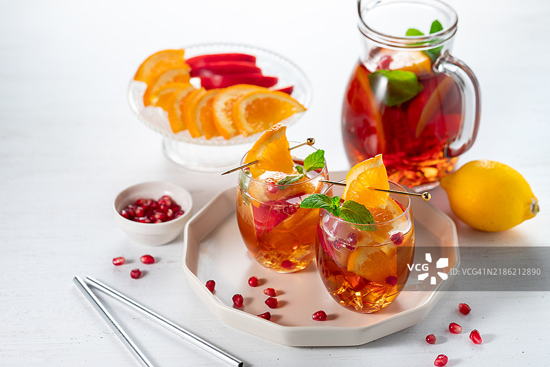 清新的桑格利亚酒果汁，配有橙子、石榴籽和苹果，背景为白色木质桌面图片素材
