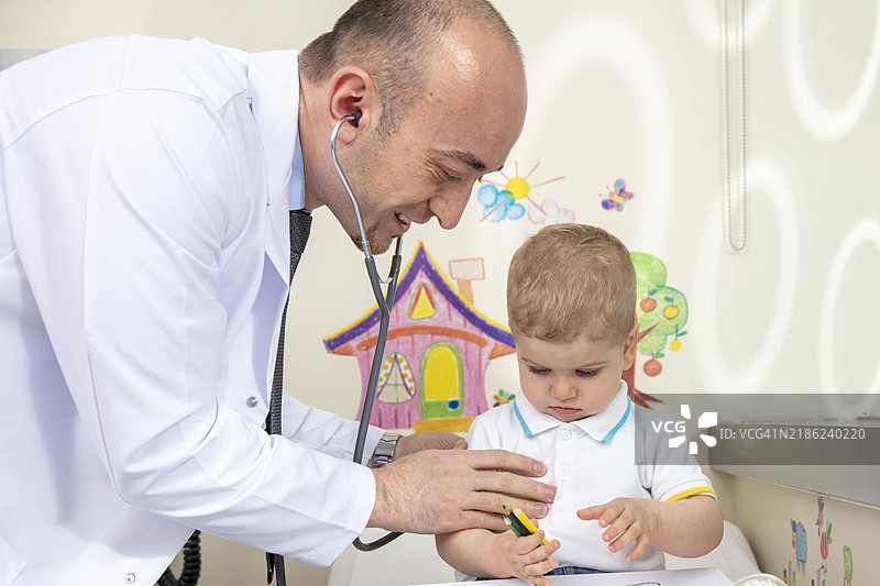 医生正在检查小男孩。小男孩正在画画。儿科。喉部控制。2岁男孩。图片素材